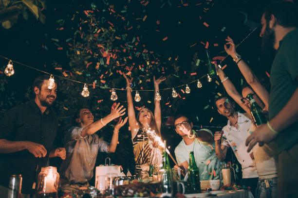 Group of young people enjoying the birthday party in backyard at night