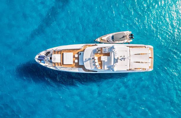 Aerial view of beautiful luxury yacht and boat in blue sea in summer. Sardinia, Italy. Top drone view of speed boat, sea coast, transparent azure water. Travel. Tropical landscape. Yachting. Seascape